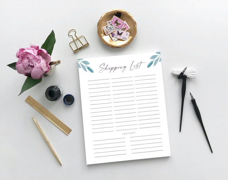 Puede incluir: Un bloc de notas imprimible de lista de la compra blanco con un dise&ntilde;o floral de acuarela azul y verde y el texto "Shopping List" en la parte superior. El bloc de notas tiene una l&iacute;nea para escribir art&iacute;culos y una secci&oacute;n para marcas.
