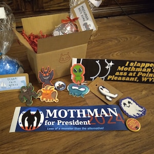 Cryptid Mystery Box - Care Package w / Mothman, Bigfoot, Fresno Nightcrawler, Nessie, weitere Kryptiden - Pins, Badebomben, Schlüsselanhänger Mystery Bag