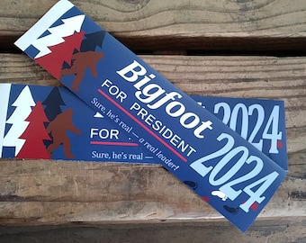 Puede incluir: Dos pegatinas de campaña política azules y blancas con el texto "Bigfoot 2024" y "FOR PRESIDENT" con el lema "Sure, he's real - a real leader!"