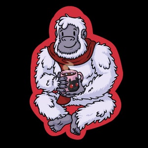 May include: A white yeti wearing a red scarf is sitting and holding a pink mug with a black cat design. The yeti is smiling and has a steaming cup of hot chocolate.