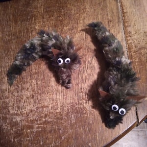 May include: Two fuzzy, brown and green worm-shaped toys with googly eyes. The worms are made of yarn and have brown felt ears.
