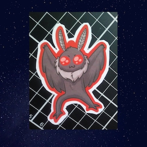May include: A sticker of a cartoon moth with large red eyes and a furry body. The moth is in a playful pose with its wings spread out. The sticker is on a black and white grid background.