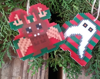 May include: Two Christmas ornaments, one with a pixelated reindeer and the other with a pixelated ghost. Both ornaments are red, green, and white.