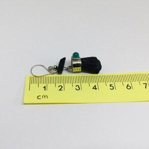 May include: Black and green gemstone earrings with a silver setting. The earrings are approximately 4 cm long.