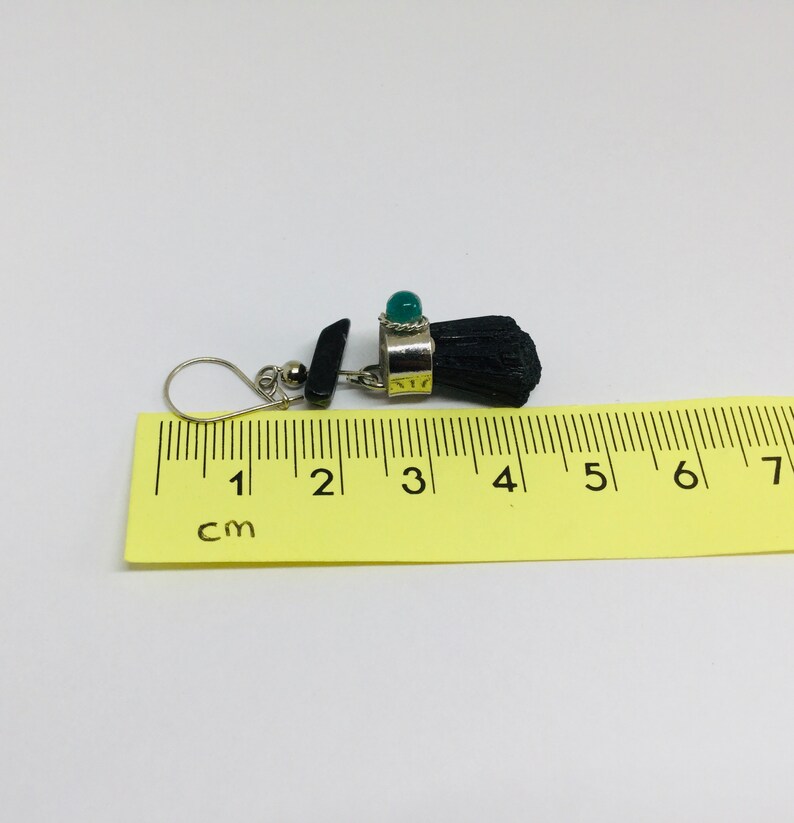 May include: Black and green gemstone earrings with a silver setting. The earrings are approximately 4 cm long.