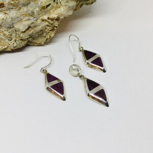 May include: A set of silver earrings and a pendant with purple and white diamond-shaped stones.