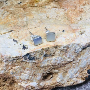 May include: A pair of silver stud earrings with square-shaped white mother-of-pearl stones.