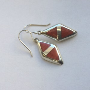 May include: A pair of silver earrings with a diamond-shaped red stone set in each earring.