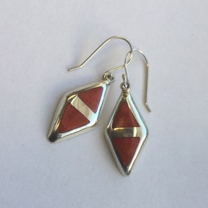 May include: A pair of silver dangle earrings with red and white geometric stone accents.