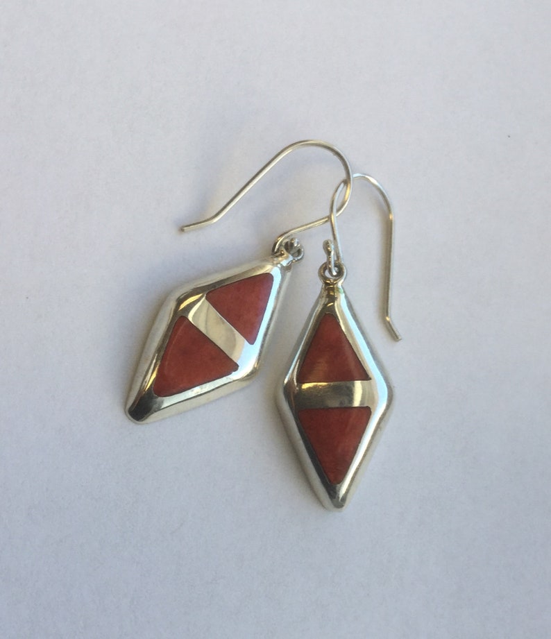 May include: A pair of silver dangle earrings with red and white geometric stone accents.