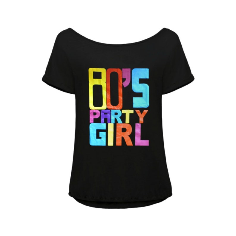 K&ouml;nnte beinhalten: Schwarzes Off-Shoulder-T-Shirt mit dem Text "80'S PARTY GIRL" in bunten Blockbuchstaben. Das Shirt hat kurze &Auml;rmel und einen runden Ausschnitt, perfekt f&uuml;r eine Retro-Party oder den Alltag.