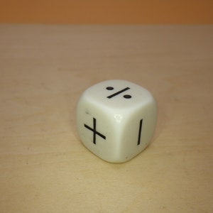 May include: White plastic dice with black symbols. The symbols are a plus sign, a vertical line, and a percent sign.