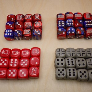 May include: Four sets of dice, each with a different design. The first set is red and blue with a Union Jack and a circle design. The second set is red and blue with a star design. The third set is red with a sun design. The fourth set is gray with a cross design.