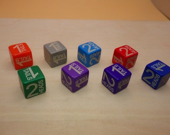 May include: Eight colorful dice with the words "Heads" and "Tails" and the numbers "1" and "2" printed on them. The dice are in various colors, including red, blue, green, purple, and gray.