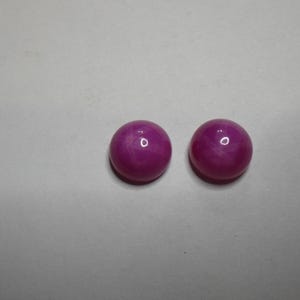May include: Two round pink gemstones with a star-like pattern inside.