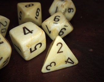 May include: A set of six white dice with black numbers. The dice are made of a marbled material and have a speckled appearance. The numbers on the dice are 1, 2, 3, 4, 5, and 6.