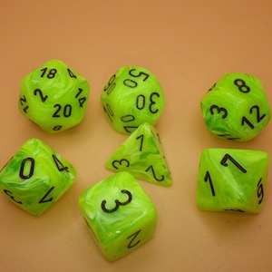 May include: Set of six green and white swirl dice with black numbers. The dice are a d4, d6, d8, d10, d12, and d20.