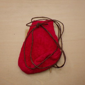 May include: A small, red leather pouch with a drawstring closure. The pouch is tied with a brown cord.
