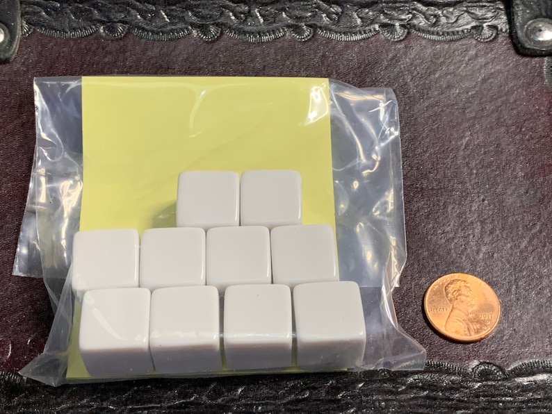 May include: A set of ten white plastic dice in a clear plastic bag with a yellow paper backing.