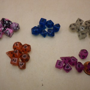 May include: A collection of 10 different colored dice, including pink, blue, orange, and clear. The dice are translucent and have black numbers on them.