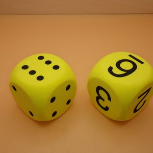 May include: Two yellow foam dice with black numbers. One die has the numbers 1, 2, 3, 4, 5, and 6. The other die has the numbers 1, 2, 3, 6, 8, and 9.