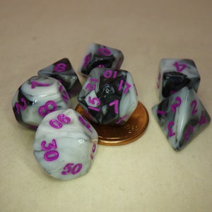 May include: Six black and white marbled dice with purple numbers. The dice are scattered on a light brown surface.