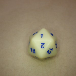 May include: A twenty-sided die with an off-white, opaque finish and bold blue numerals. The die features a geometric polyhedral shape with triangular faces, displaying numbers including 1, 2, 8, 10, 12, 14, and 18 clearly printed in a sans-serif font.