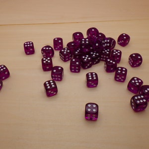 May include: A pile of purple dice with white dots on a light brown surface.
