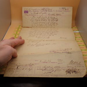 May include: An antique document from The Atchison, Topeka & Santa Fe Railway Company, dated May 19, 1903. The document is yellowed with age and features handwritten text and signatures. A hand is holding the document.