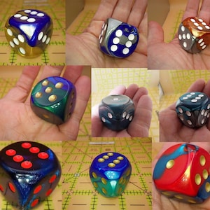 May include: A collection of multi-colored six-sided dice featuring various finishes including metallic, pearlescent, and glitter effects. Each die displays contrasting pips in colors such as white, gold, and red, showcasing a range of vibrant hues.