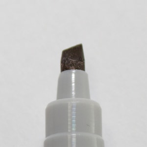 May include: Close-up of the tip of a brown marker with a chisel tip.