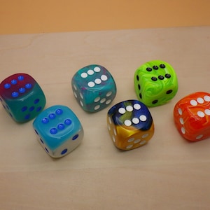 May include: Six colorful dice with white dots on each side. The dice are made of clear plastic with swirls of color. The colors are pink, blue, green, yellow, orange, and black.