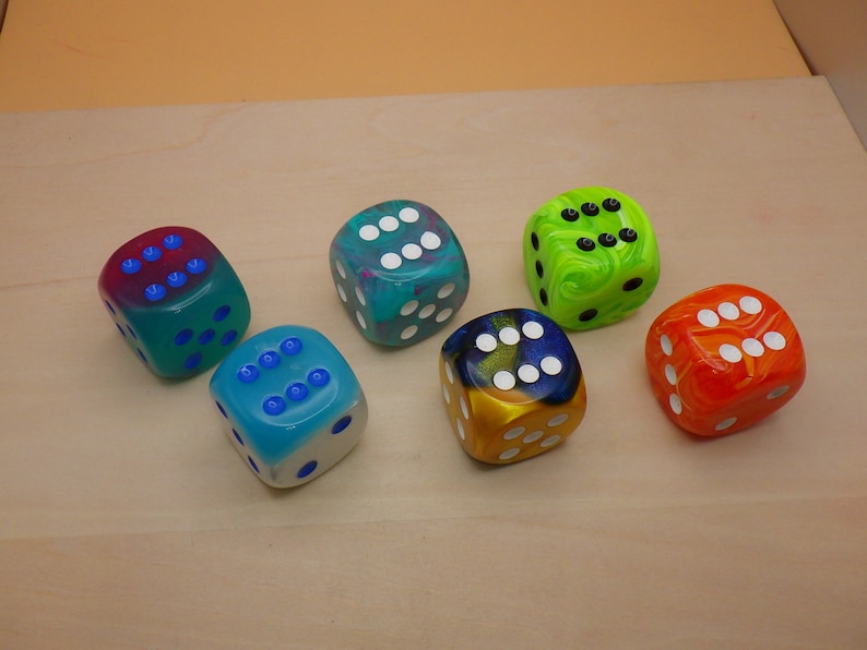 May include: Six colorful dice with white dots on each side. The dice are made of clear plastic with swirls of color. The colors are pink, blue, green, yellow, orange, and black.