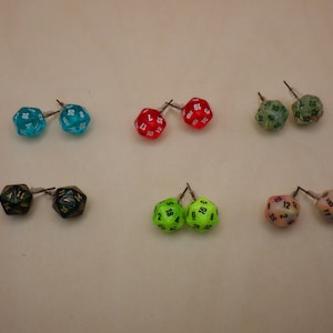 May include: A set of ten colorful dice earrings, each with a different number of sides. The dice are made of clear plastic and have black numbers on them. The earrings are perfect for anyone who loves dice or wants to add a touch of whimsy to their look.
