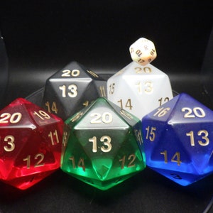 May include: Five 20-sided dice in different colors: red, black, white, green, and blue. Each die has gold numbers on the faces. The dice are arranged in a circle with a smaller white die on top.