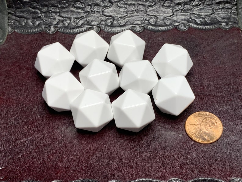 May include: Ten white, opaque, plastic, twelve-sided dice on a burgundy surface. A copper penny is to the right of the dice.