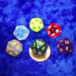 May include: Six different colored dice with gold numbers. The dice are on a blue velvet surface.