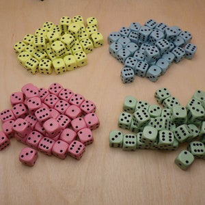 May include: Four piles of dice in different colors: yellow, pink, light green, and blue. Each pile contains approximately 40 dice.