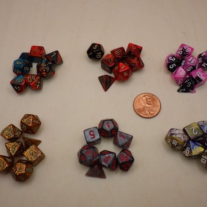 May include: A collection of ten sets of dice, each set containing multiple dice. The dice are made of various materials, including plastic, metal, and glass. The dice are in a variety of colors, including red, blue, green, black, white, and gold. The dice are numbered 1 through 6.
