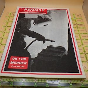 May include: Vintage "The Pennsy" magazine cover featuring a black and white image of a worker welding. The cover has a red and white border with the text "OK FOR MERGER" and "See Page One". The magazine is on a green and clear grid.