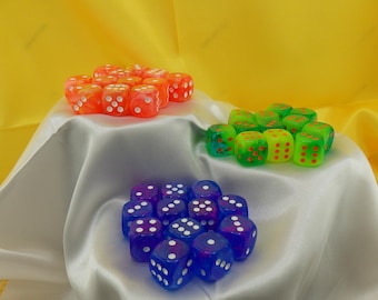 May include: A set of 18 dice in three colors: orange, green, and blue. Each die has white dots on the sides. The dice are arranged in three groups on a white satin surface.