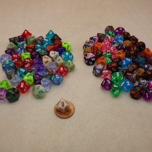 May include: A large group of colorful, iridescent dice with white numbers. The dice are made of clear plastic with glitter embedded in the plastic. There is a single die in the center of the image, which is a 9-sided die.