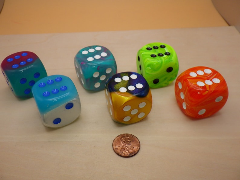 May include: Six colorful dice with white dots. The dice are made of clear plastic with swirls of color. The colors are blue, green, yellow, orange, and red.