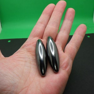 May include: Two smooth, black, oval-shaped magnets.