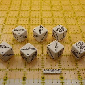 May include: Seven white dice with black illustrations of weapons and other symbols. The dice are arranged on a yellow grid. The text "CAVELOOT.COM 1" is visible. Each die has different images on each side.