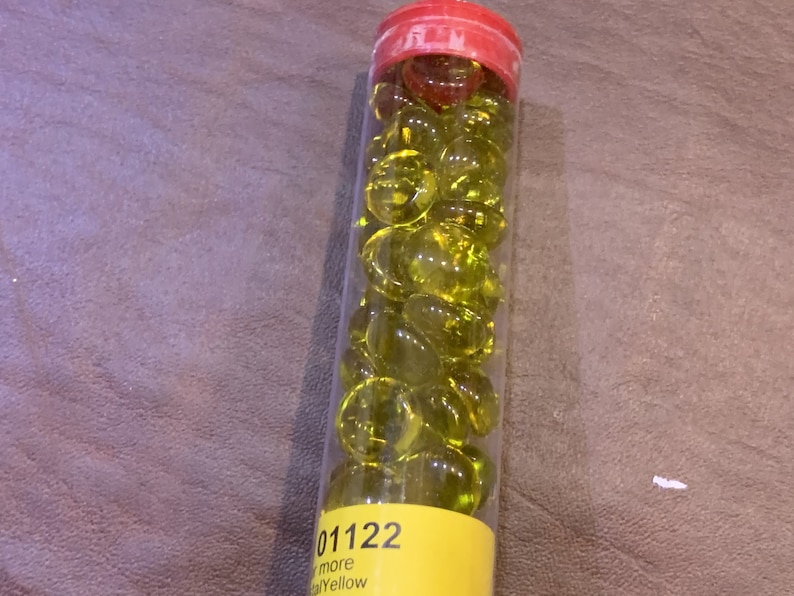 May include: A clear plastic tube filled with small, bright yellow glass beads. The tube has a yellow label with the text "01122" and "more Yellow".