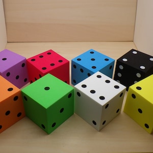 May include: Eight colorful foam dice with black dots. The dice are in various colors, including purple, red, blue, black, orange, green, white, and yellow.