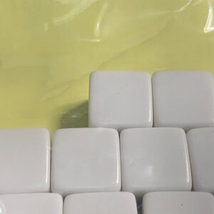 May include: A set of white ceramic tiles arranged in a staggered pattern. The tiles are smooth and glossy.