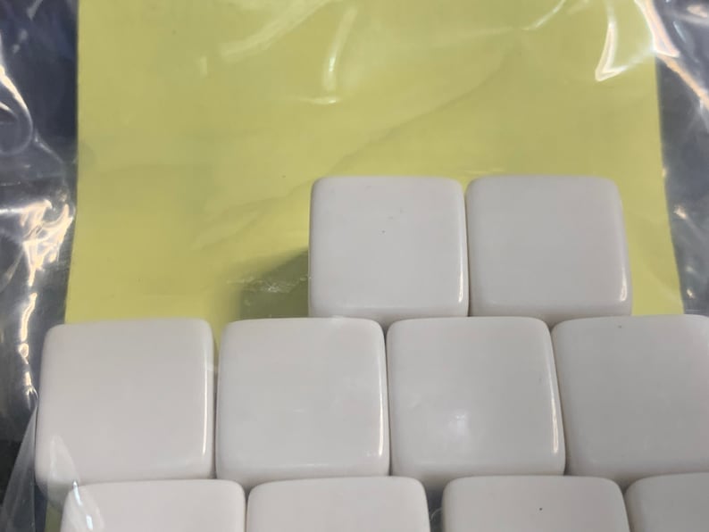 May include: A set of white ceramic tiles arranged in a staggered pattern. The tiles are smooth and glossy.