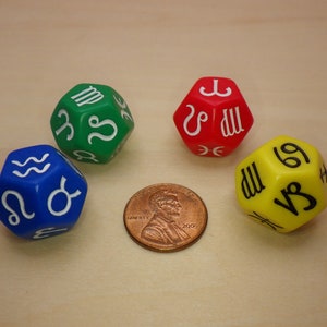 May include: Four 12-sided dice with zodiac symbols. The dice are green, red, blue, and yellow. The dice are on a wooden surface.